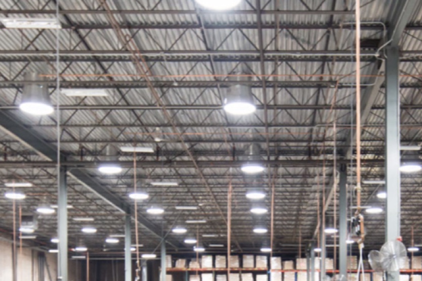 Solatube diffusers lighting an open-ceiling high-bay warehouse interior, with exposed steel structure and racking below